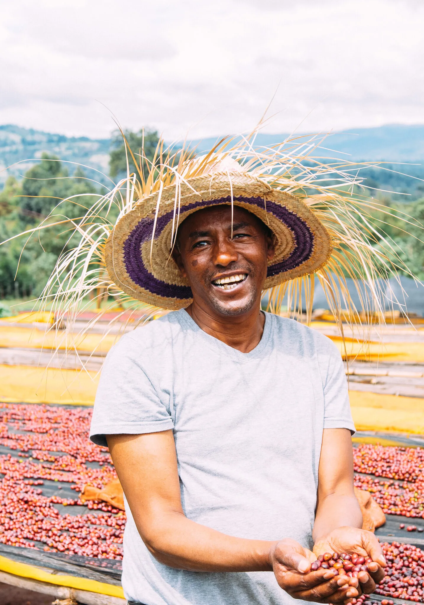 Coffee producer smiling at a drying station in Ethiopia, part of PASSENGER Coffee’s sourcing.