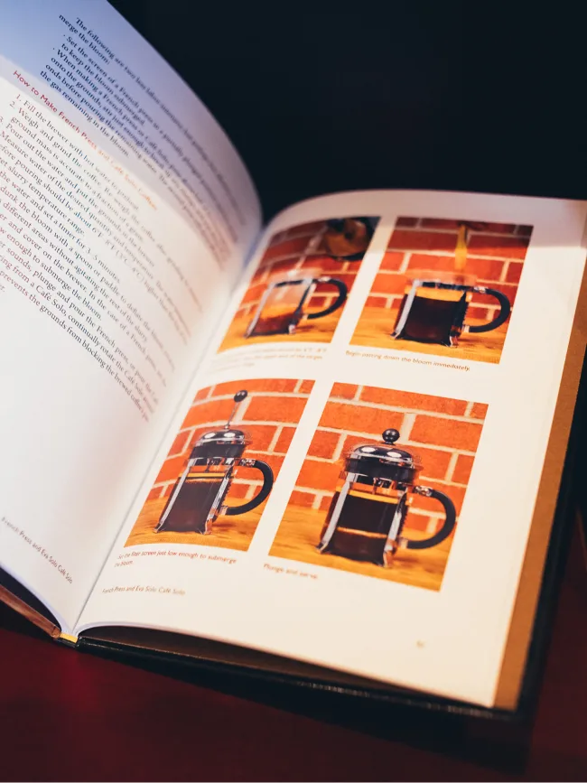 Aufgeschlagenes Buch „Everything but Espresso“ mit Fotoserie einer French Press